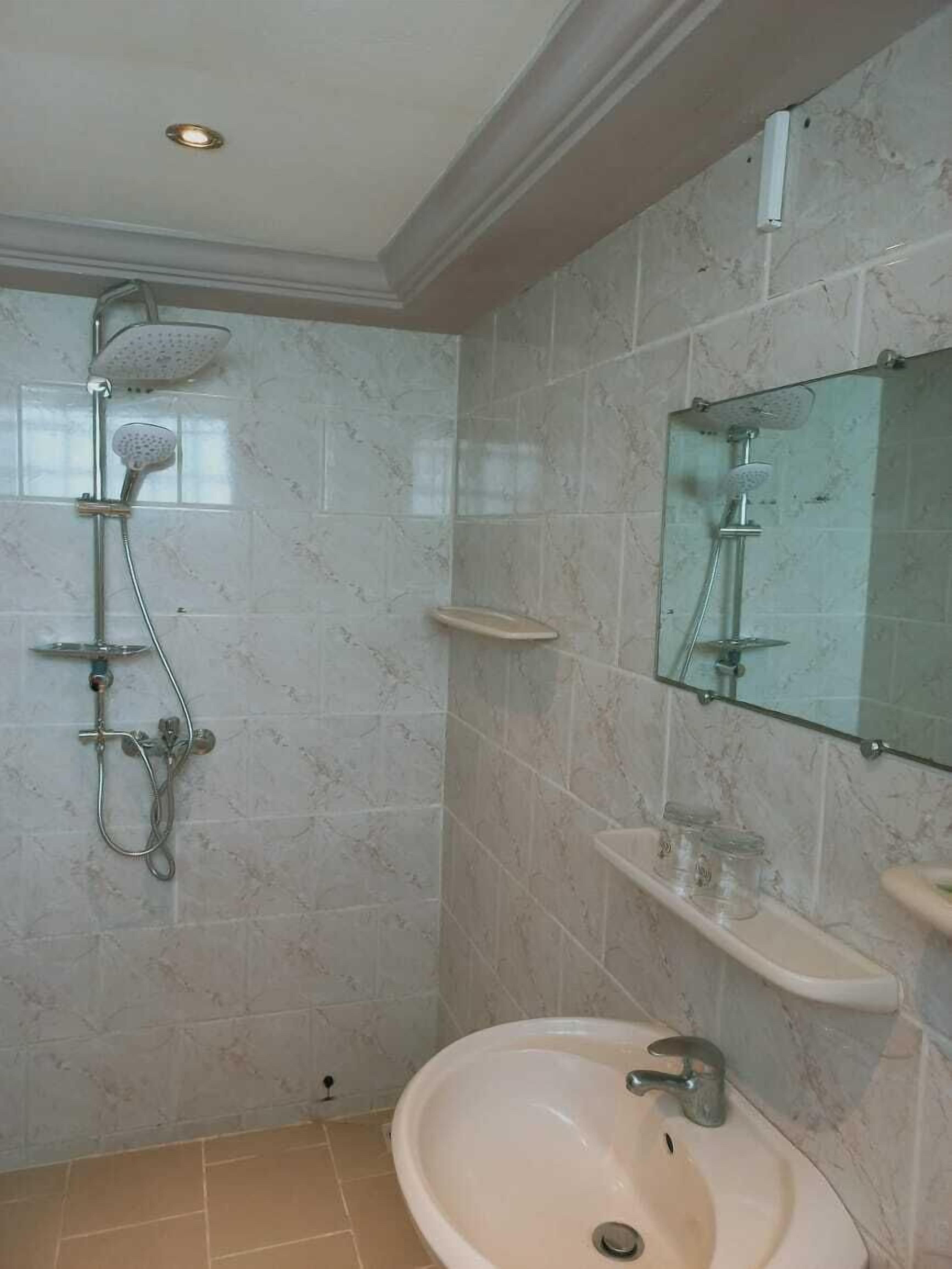 Une salle de bain avec une douche, un lavabo et un miroir.