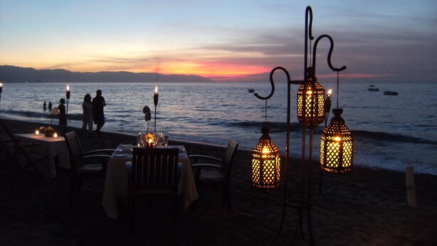 Un restaurant situé en bord de mer, avec des tables et des chaises, offrant une vue sur l’océan.