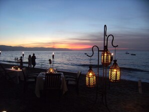 A beachside restaurant with tables and chairs, overlooking the sea.