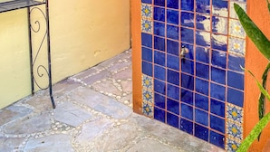 Une porte recouverte de carreaux de céramique, une douche, un escalier en colimaçon en métal et une plante en pot.