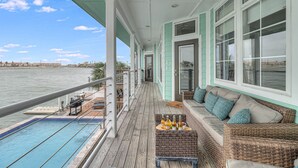 A balcony with a pool, seating area, and a view of the water. - Sunsets | Private Pool & Hot Tub | Green Lights | Boat Lift | Icemaker (Rockport)