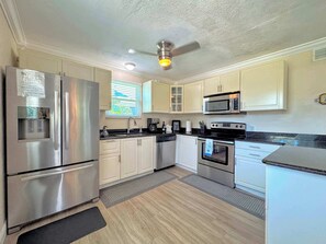 A modern kitchen with stainless steel appliances, white cabinetry, and a black countertop.