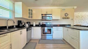A kitchen with white cabinets, a stainless steel oven, a microwave, and a coffee maker.