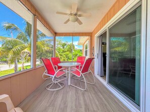 A balcony with a table and chairs, a ceiling fan, and a view of palm trees. - 231 Dundee Cozy Home Short Walk to Beach (Fort Myers Beach)