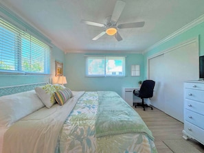 Un dormitorio con cama, escritorio, silla y ventilador de techo.