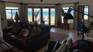 A spacious living room with a leather sofa, a coffee table, and a view of the beach through large glass doors. - Beachfront House in Las Concha's.   (Puerto Penasco)