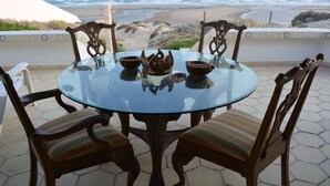 A round glass table with four chairs, a decorative centerpiece, and a view of the ocean and beach. - Beachfront House in Las Concha's.   (Puerto Penasco)