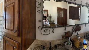 A hallway with antique decor, including a horse sculpture, a mirror, and a tiled wall. - Beachfront House in Las Concha's.   (Puerto Penasco)