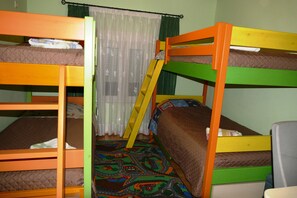 A bunk bed room with a ladder, a patterned rug, and a curtain.