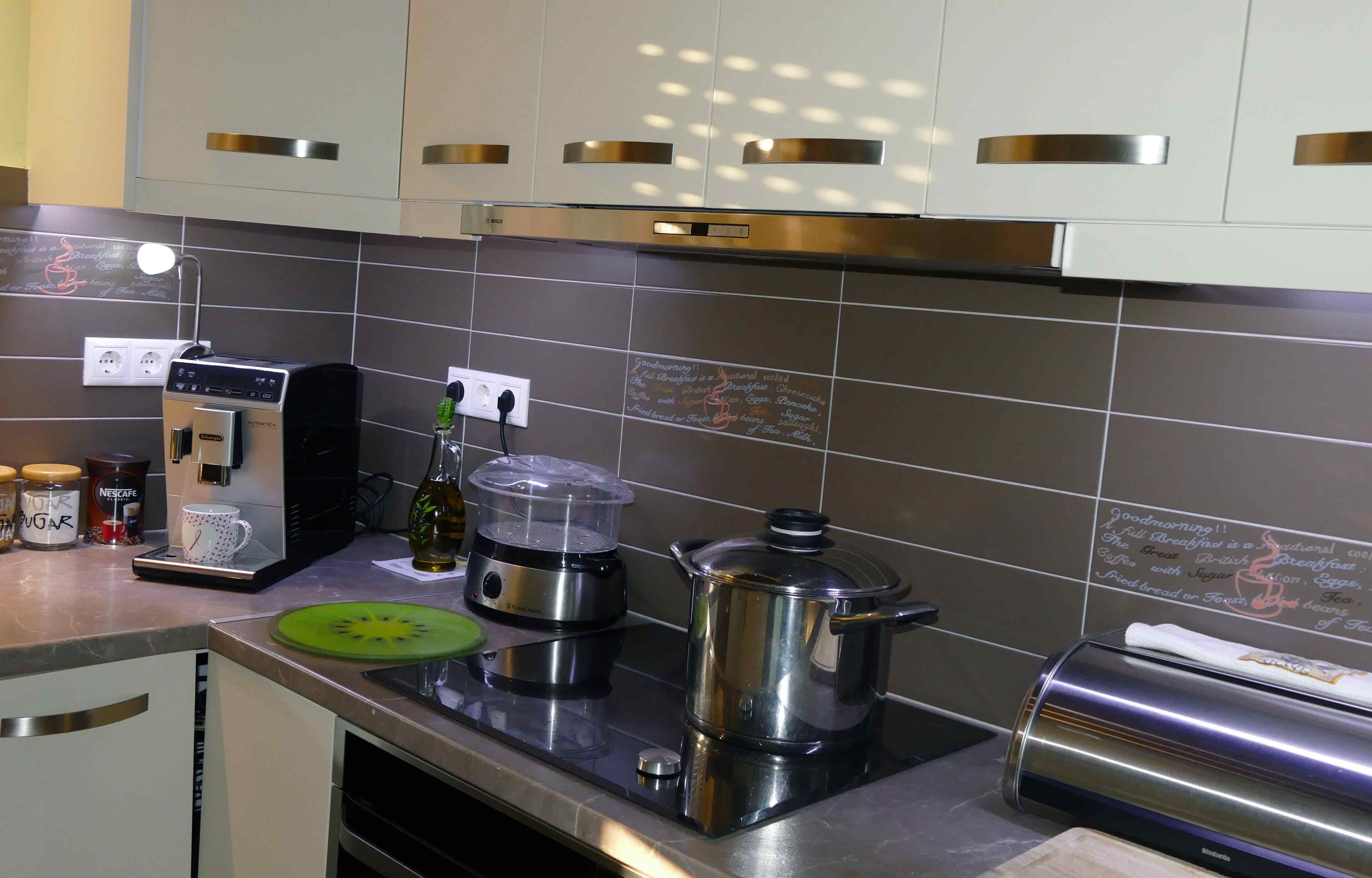 Una cocina moderna con electrodomésticos de acero inoxidable, una cafetera y un hervidor sobre la encimera.