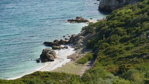 A coastal landscape with a beach, rocky outcrops, and dense greenery. - esperides holidays (Marathon)