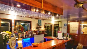 Zona bar con un bancone in legno, una ruota di timone e un espositore per il menu.