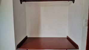 A set of three wooden shelves against a wall. - Hostal La Isla del Descanso (Puerto Villamil)