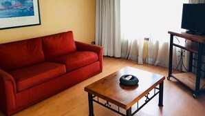 A living room with a red sofa, a wooden coffee table, a television on a stand, and a painting on the wall. - Tempo Light (Santiago)