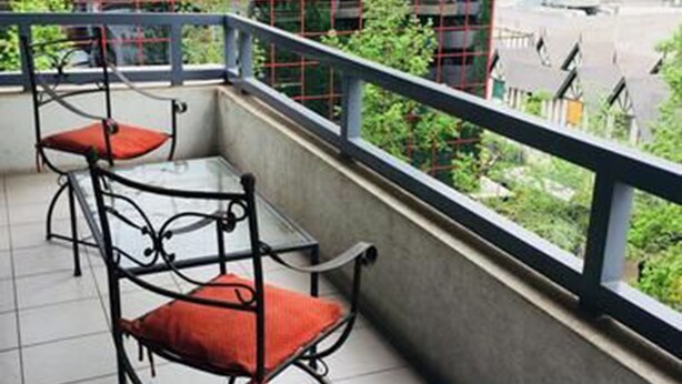 A balcony with metal chairs and a table, overlooking a cityscape with buildings. - Tempo Light (Santiago)