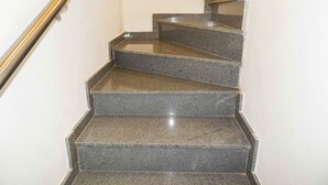 Una serie de escalones de granito con barandilla metálica, que conducen a un piso superior.