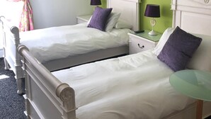 Une chambre avec deux lits, un mur d’accent de couleur verte et une petite table.