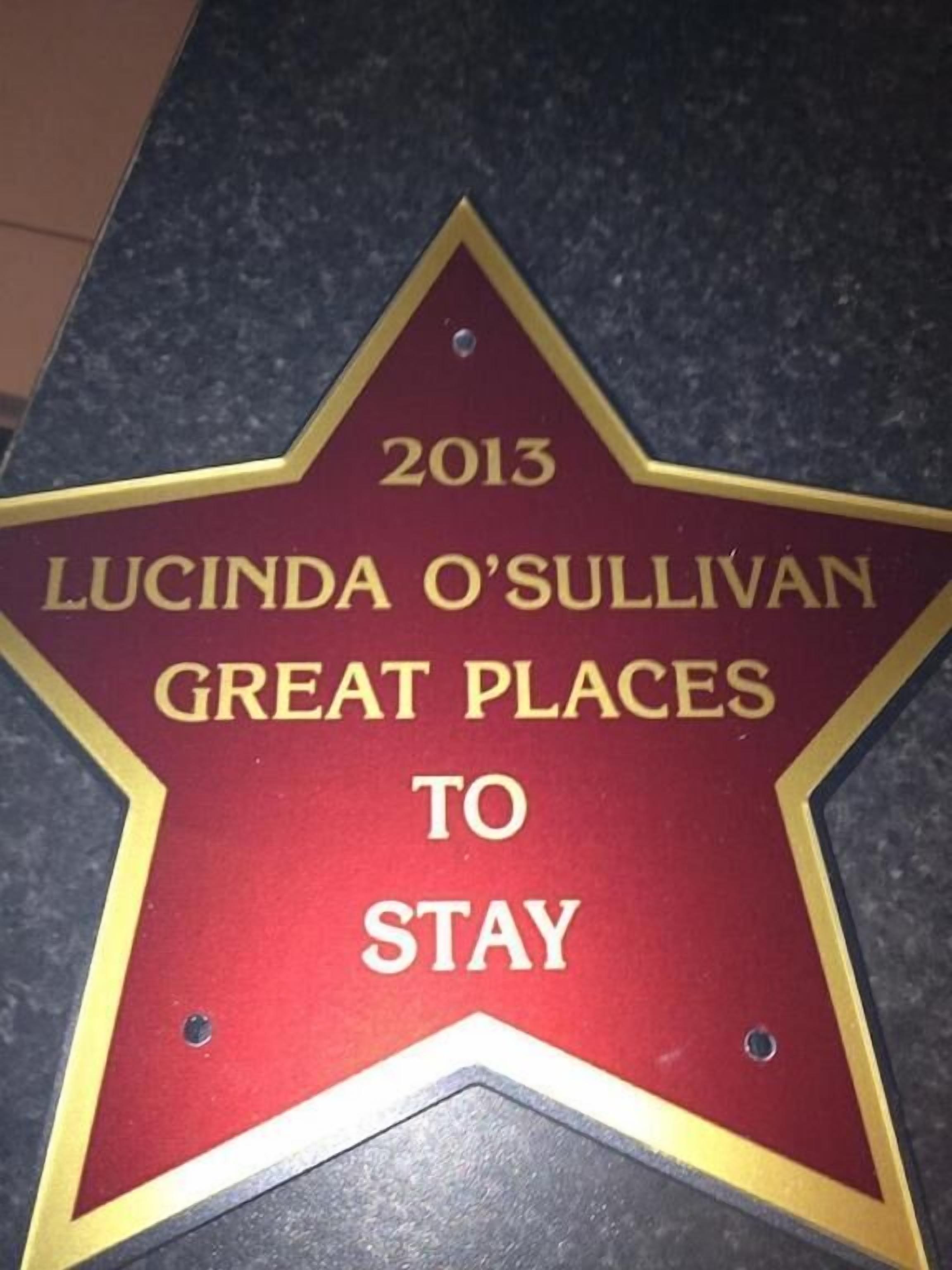 A red star-shaped plaque with gold trim, mounted on a dark surface.
