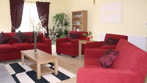 Un salon avec des canapés rouges, une table basse en bois et une bibliothèque.