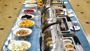 Una mesa de buffet con diversos alimentos y utensilios para servir.