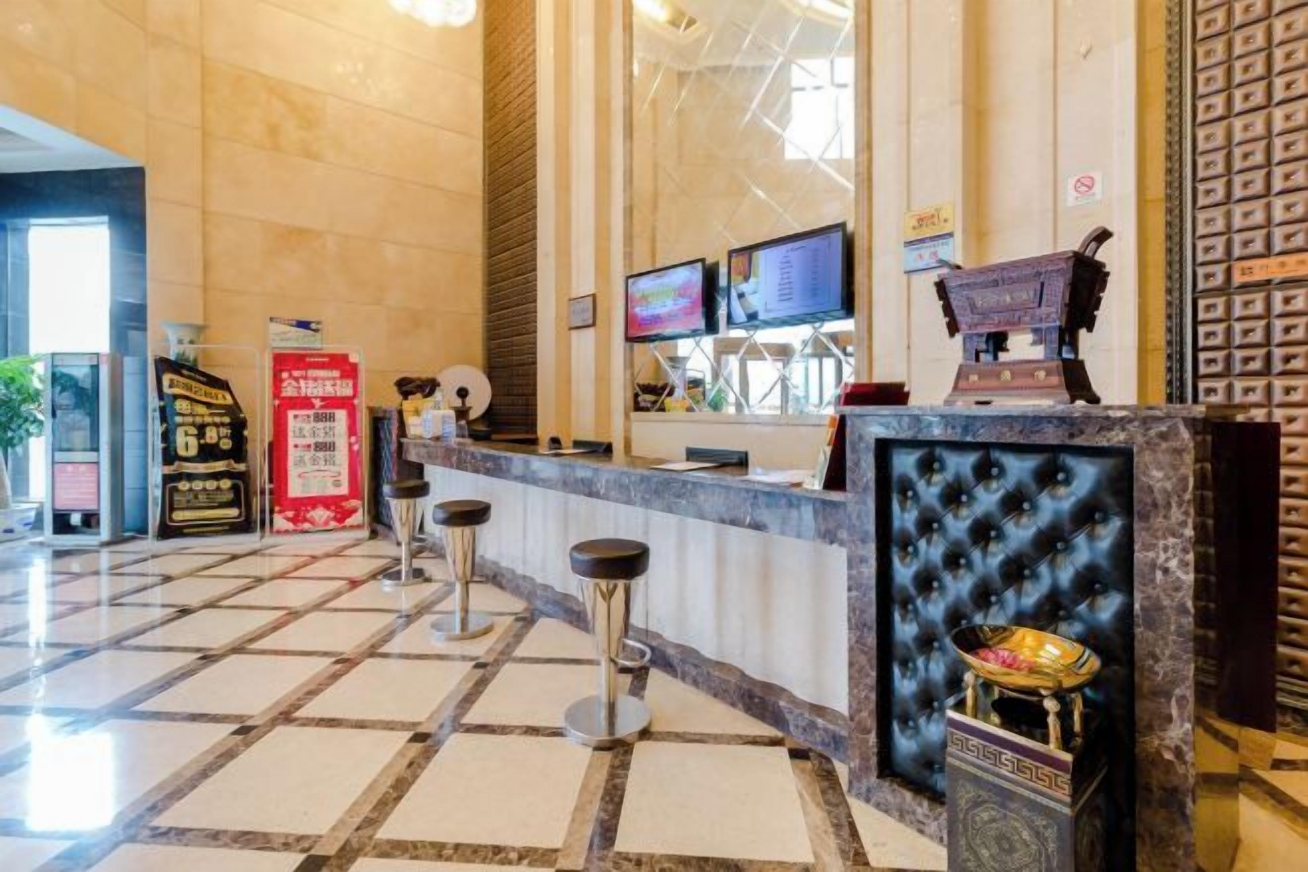 Zona de recepción de hotel con mostrador de check-in, varias pantallas y una pieza decorativa central.