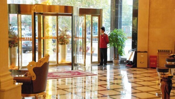 Un vestíbulo de hotel con mostrador de recepción y una planta grande en maceta.