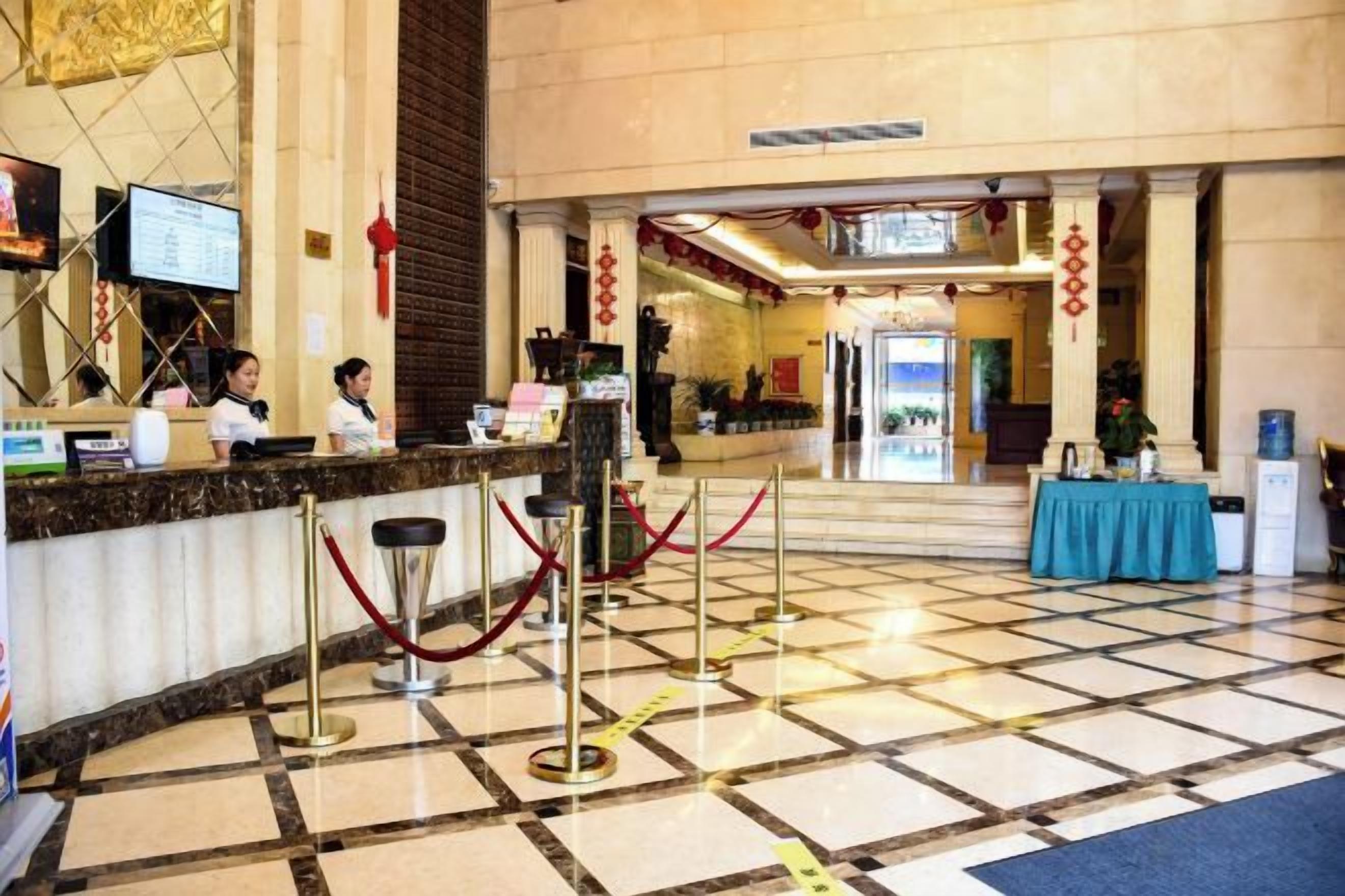 A hotel lobby with a reception desk, a check-in counter, and a blue table with a plant.