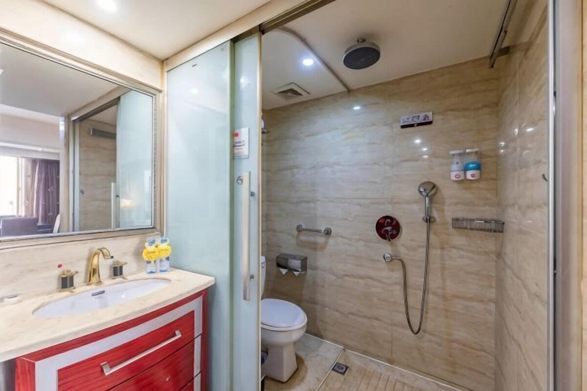 A bathroom with a glass shower enclosure, a toilet, a sink with a mirror, and a vanity with drawers.