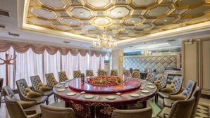 Un salón de conferencias con una mesa redonda, sillas de respaldo alto y un techo decorativo.