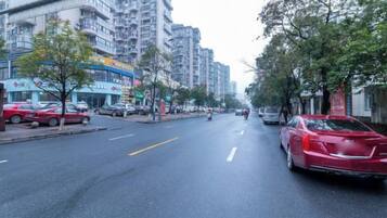 Una calle urbana con edificios, coches aparcados y árboles.