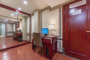 A hotel room with a wooden desk, a computer, a chair, a mirror, and a door with a sign. - Chen Xiang Guest Hotel (Xinyu)