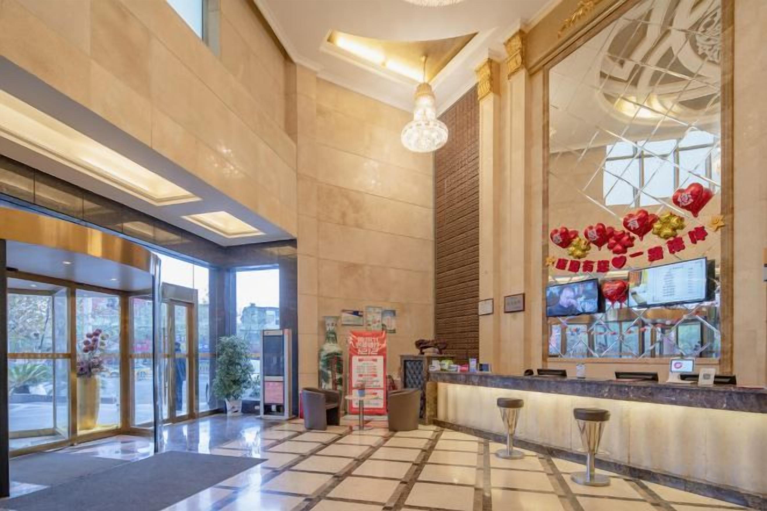Eine Hotelhalle mit einer Rezeption, großen Fenstern und einer dekorativen Wand.