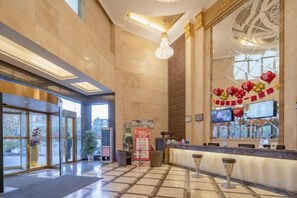 A hotel lobby with a reception desk, large windows, and a decorative wall. - Chen Xiang Guest Hotel (Xinyu)