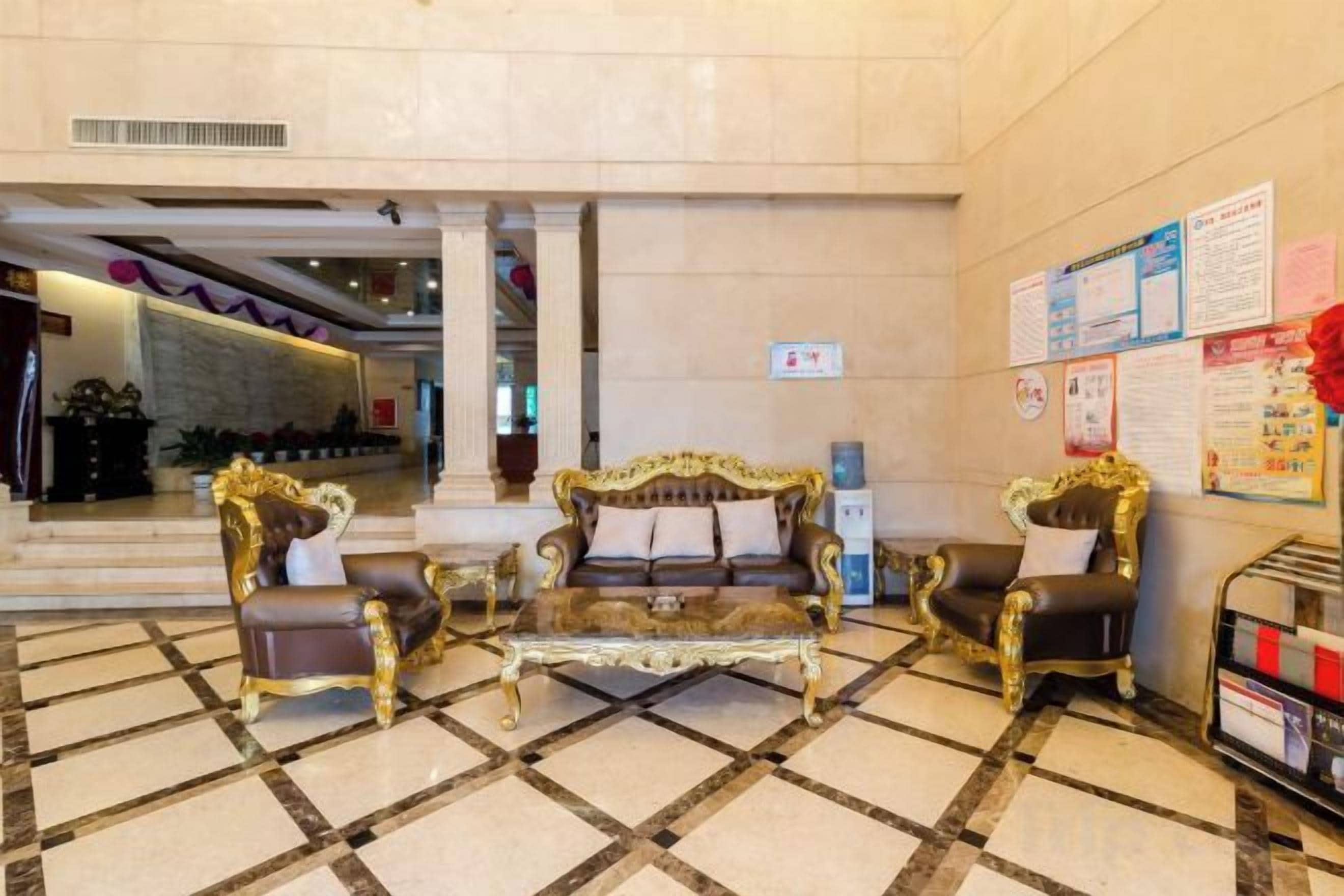 A lobby with a checkered floor, two ornate sofas, a reception desk, and a wall with informational posters.