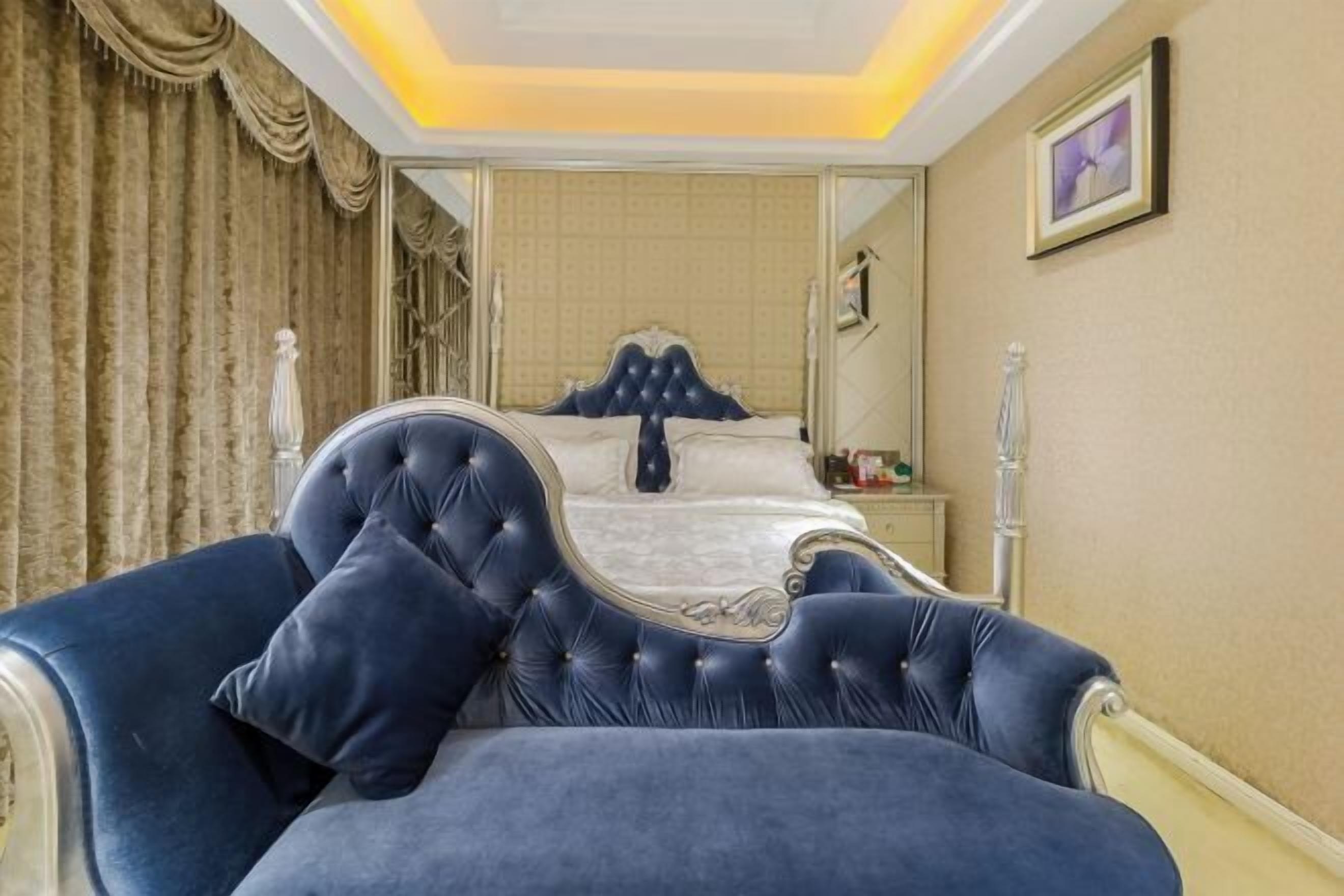 Un dormitorio con una cama grande, una silla y una mesita de noche.