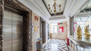 A hotel lobby with a marble floor, elevator, and a chandelier. - Chen Xiang Guest Hotel (Xinyu)