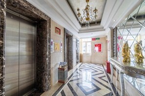 A hotel lobby with a marble floor, elevator, and a chandelier. - Chen Xiang Guest Hotel (Xinyu)