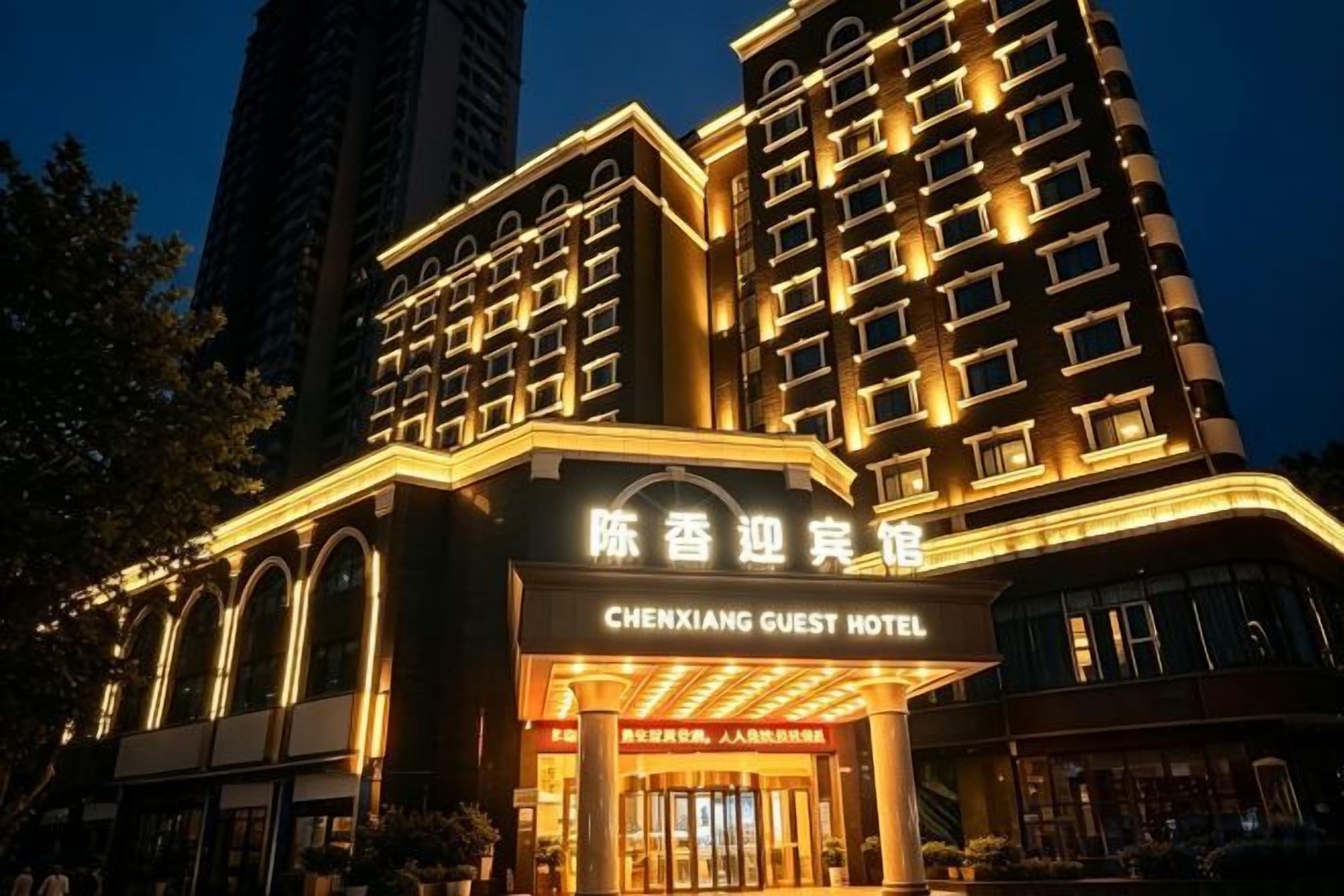 Un hôtel à plusieurs étages, reconnaissable à son enseigne bien visible indiquant « CHENXIANG GUEST HOTEL ».