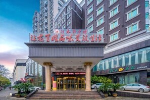 A hotel entrance with a large sign, a covered entrance area, and a modern building facade.