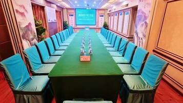 A conference room with a long table and chairs, a podium, and a screen at the front.