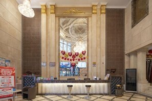 A reception area with a marble reception desk, a large decorative window, and a chandelier. - Chen Xiang Guest Hotel (Xinyu)