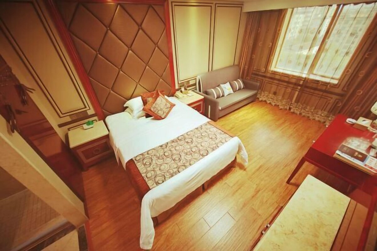 A hotel room with a bed, a sofa, a nightstand, and a desk.