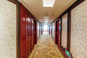 A hotel hallway with patterned carpet, wooden doors, and a carpeted floor. - Chen Xiang Guest Hotel (Xinyu)