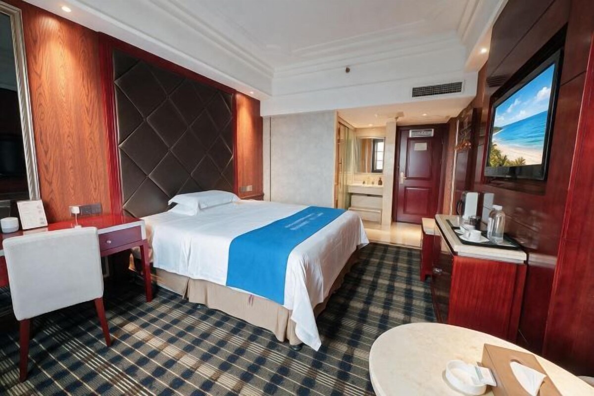 A hotel room with a bed, a desk, a chair, a bathroom, and a television.