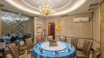 A conference room with a round table, chairs, and a chandelier.