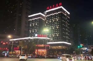 Un hotel de varios pisos con señalización iluminada y una fachada bien iluminada.