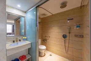 A bathroom with a sink, mirror, toilet, and shower.