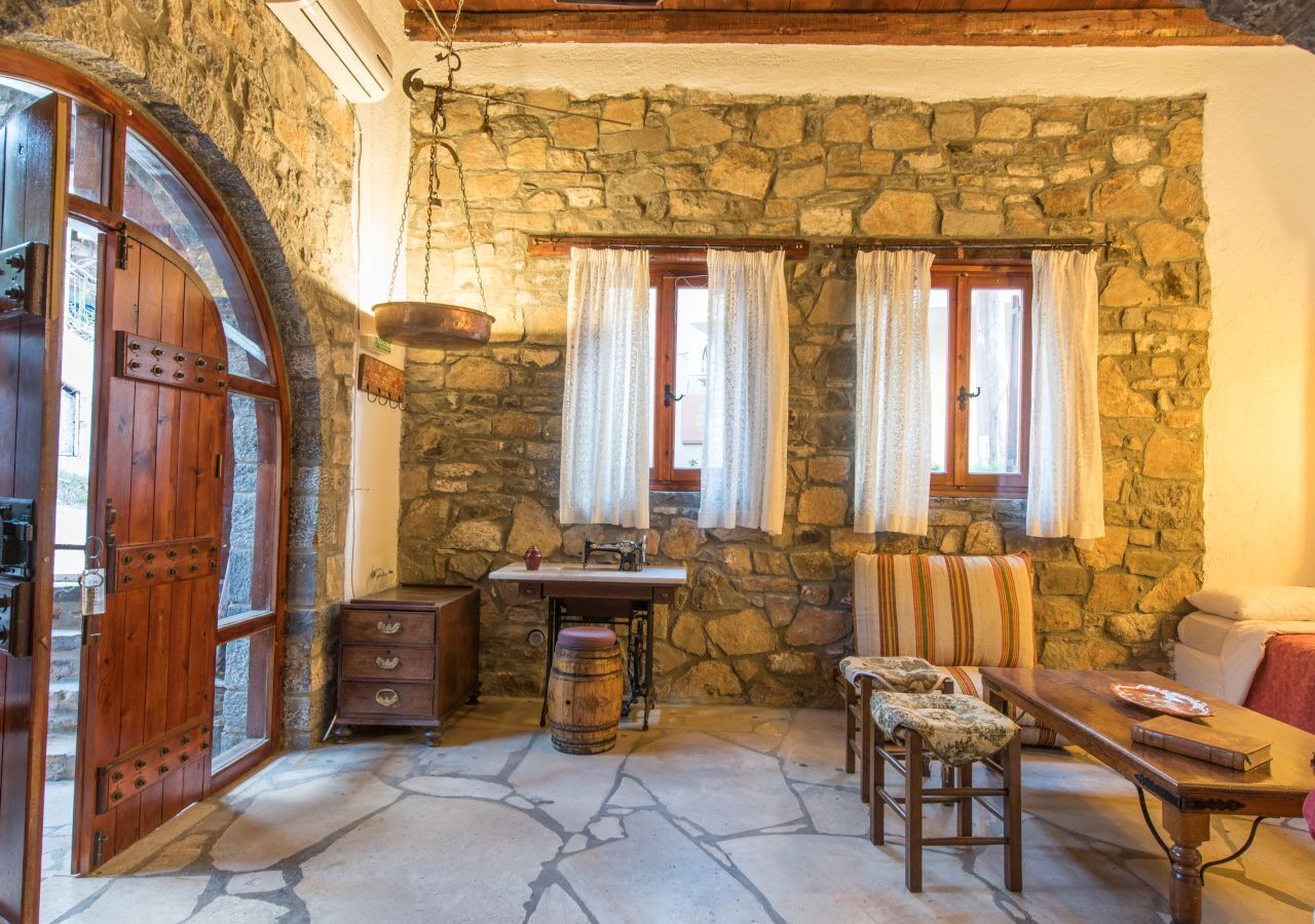 Une pièce rustique aux murs de pierre, avec une porte en bois, une petite table, un banc et un canapé.