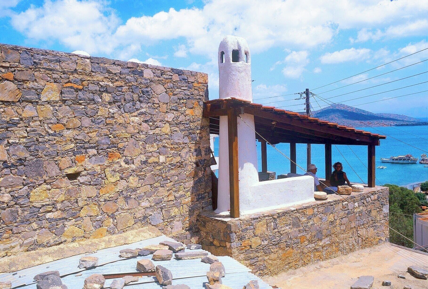 Un edificio de piedra con una torre blanca y un porche que da a un cuerpo de agua.