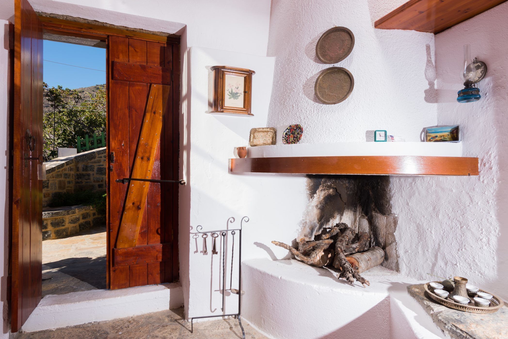 Un interno rustico con una porta in legno, una parete in pietra e un camino con legna.